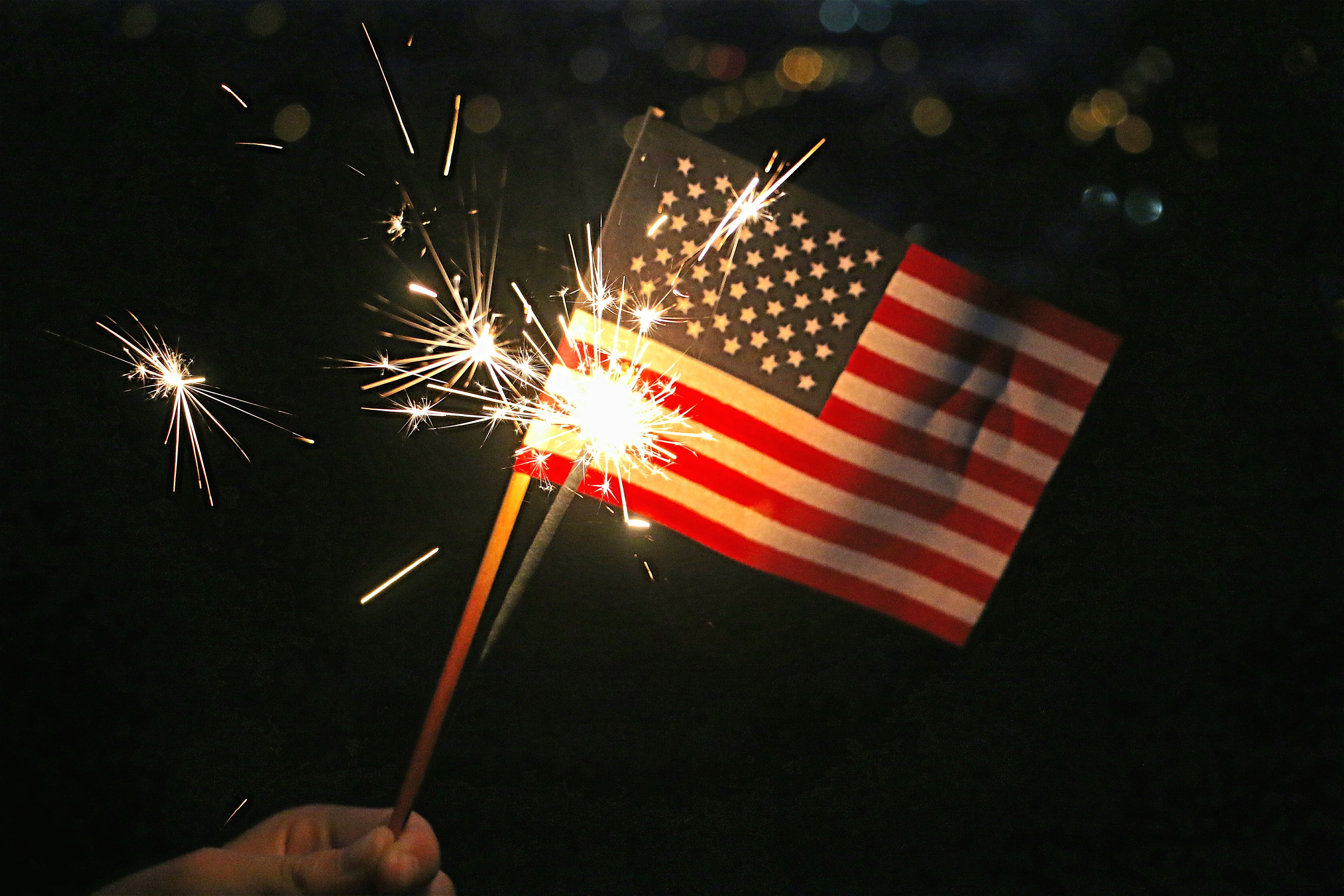 hand-holding-small-american-flag-and-lighted-spark-